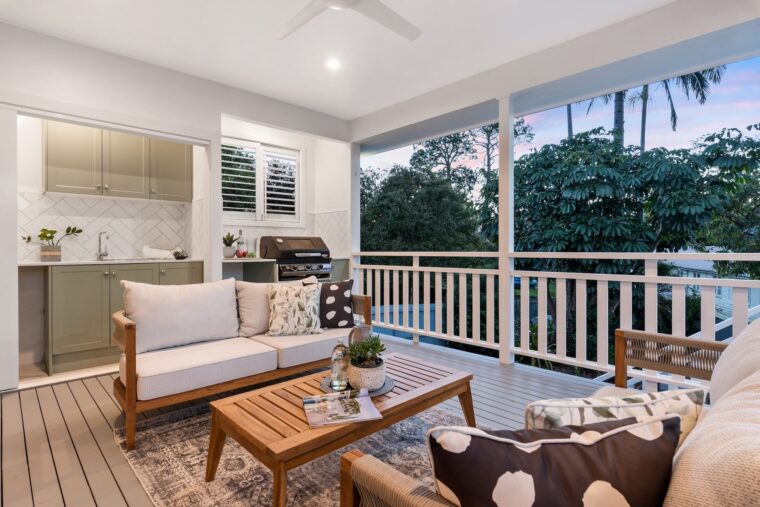 An image of a large outdoor entertaining deck with a seating area and a small kitchen.