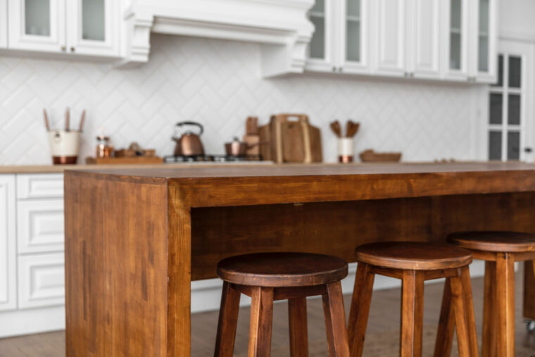 Una isla de cocina de madera y taburetes de bar a juego en una cocina blanca.