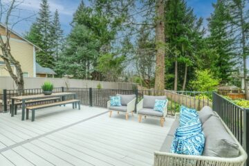An image of a backyard deck with a dining table, outdoor chairs, and an outdoor couch.
